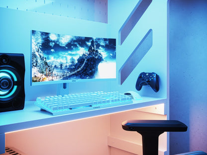 A sleek and modern Recoil gaming bed setup bathed in cool blue light, featuring a large monitor with a fantasy game landscape, a white mechanical keyboard, a gaming controller, and a dynamic speaker, ready for.